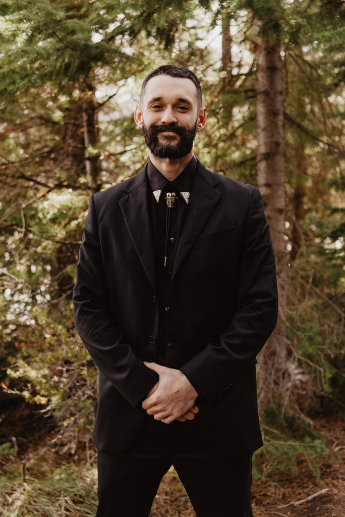 groom in all black Johnny Cash inspired wedding attire in the woods of the Tetons