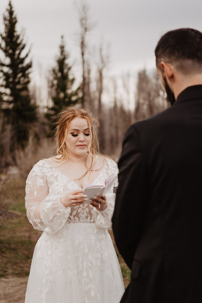 bride reading her vows at her Jackson HOle wedding ceremony in the woods