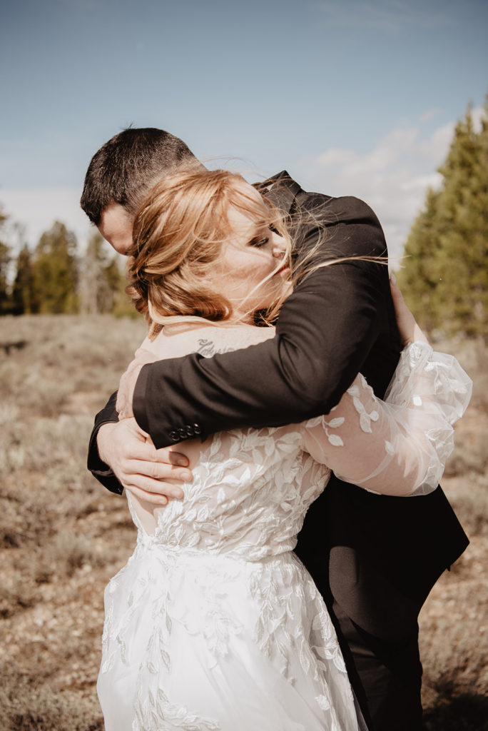 bride and groom hugging each other in a field in the mountains for their first look in Jackson Hole wedding 