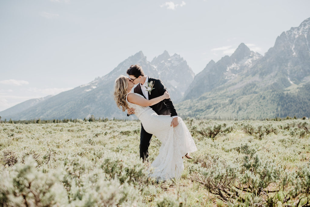 Jackson Hole wedding elopement with groom dipping his bride back and kissing her with the Grand Teton mountains in the distance