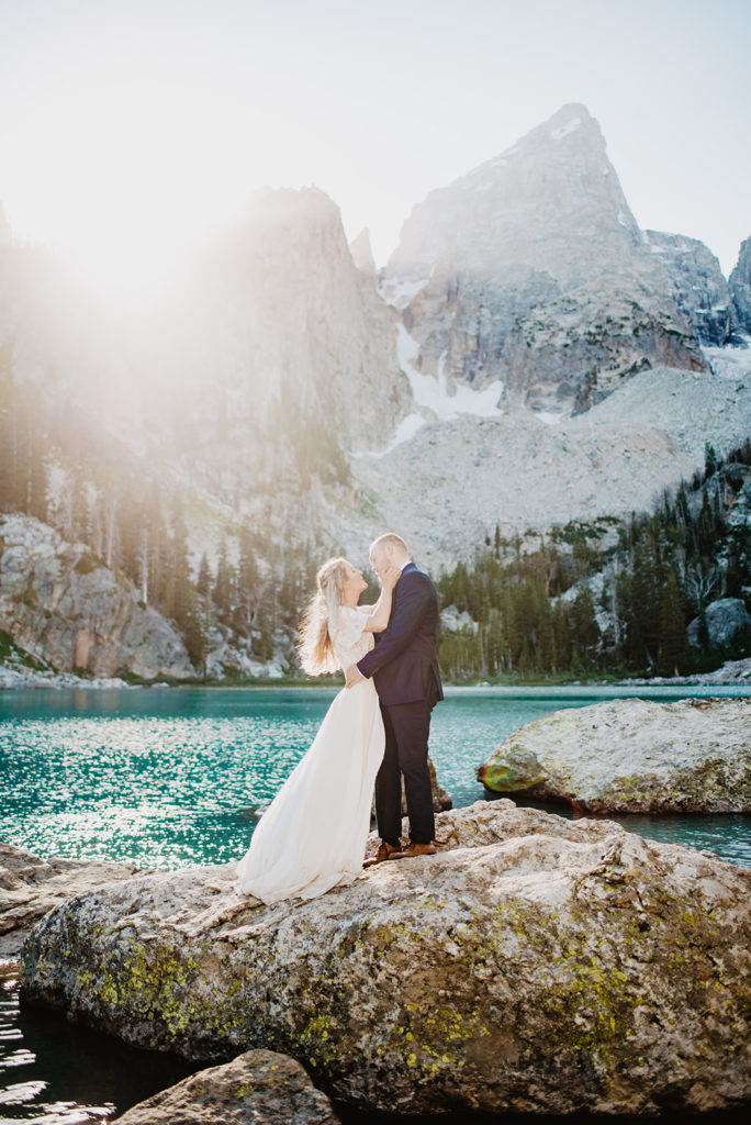 Jackson Hole wedding photographer captures bride and groom at a lake in the mountains for the Jackson Hole wedding as they embrace one another