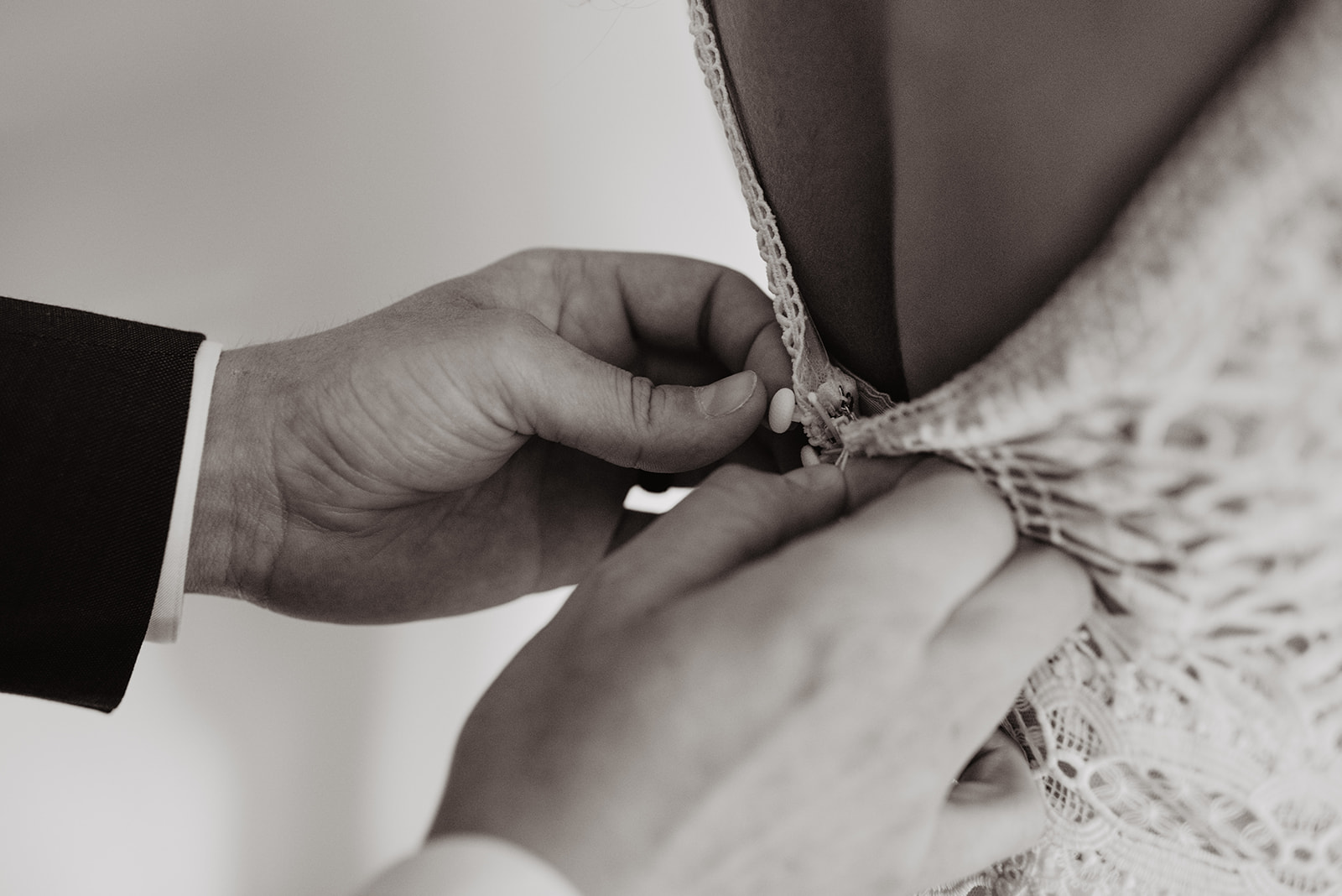 black and white wedding photo of groom buttonsing his brides lace wedding dress taken by jackson hole wedding photographers
