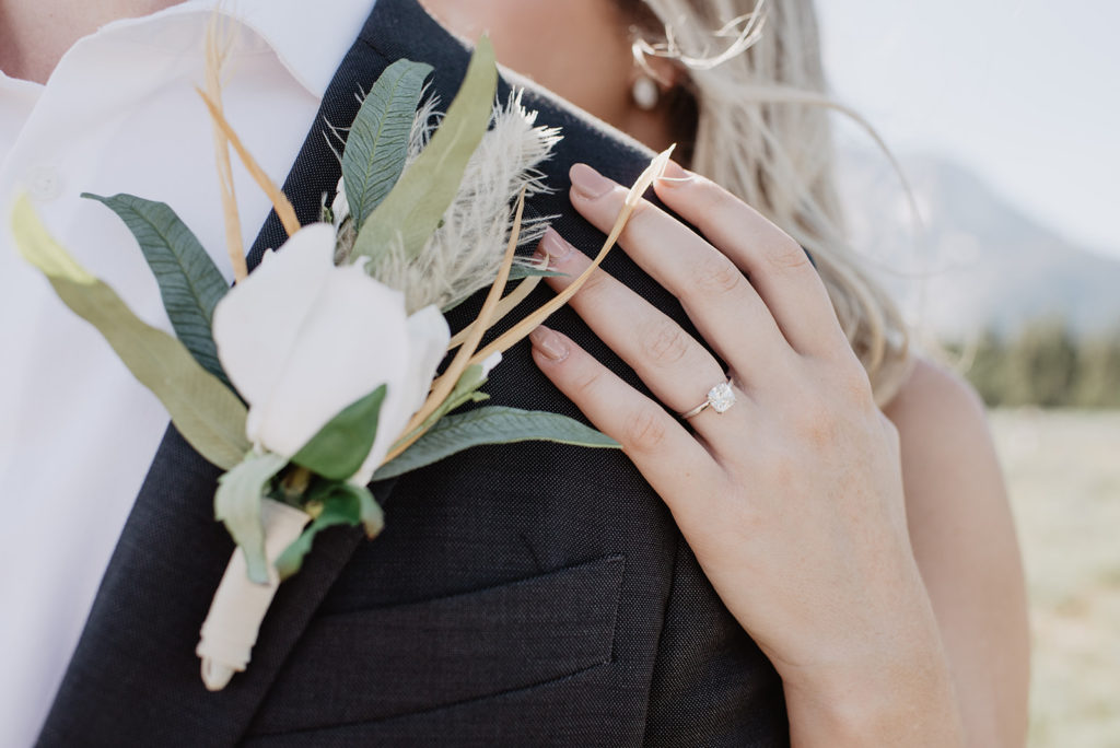 groom's boutonniere with a white rose and other boho greenery on a black suit photographed by jackson hole wedding photographers