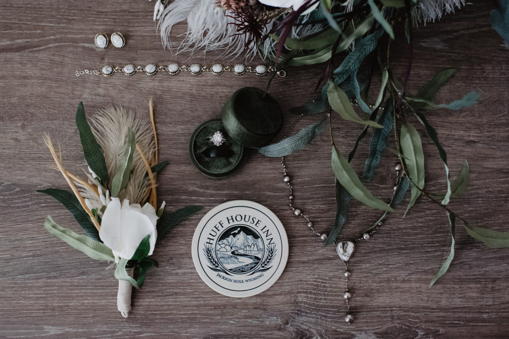jackson hole elopement photographer captures bridal and grooms details laid out on a wood table 
