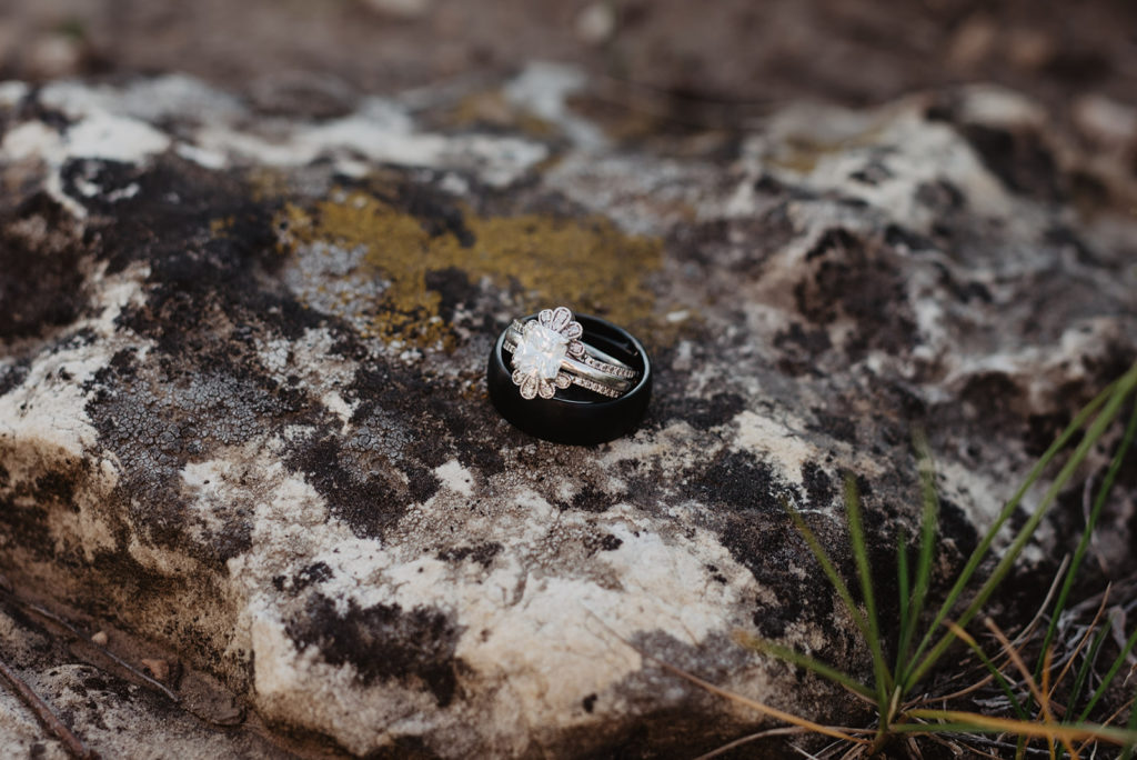 detail shot of engagement and wedding ring sitting on a rock for jackson hole flatlay photos