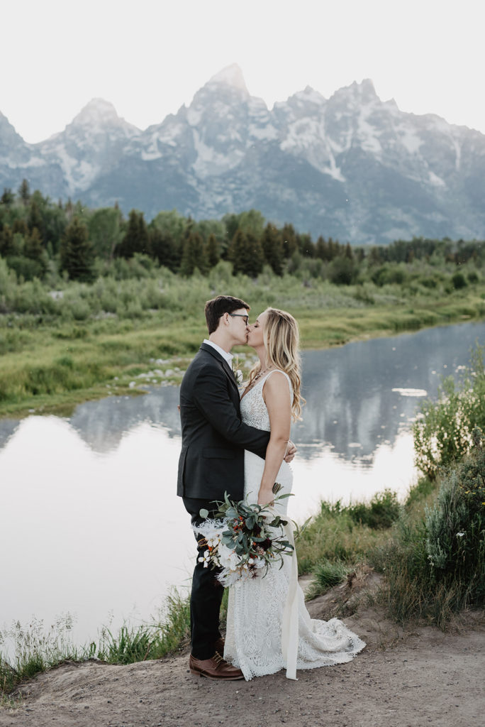 jackson hole wedding photographers photographs bride and groom kissing at Schwabacher Landing in the Tetons for their Jackson Hole wedding