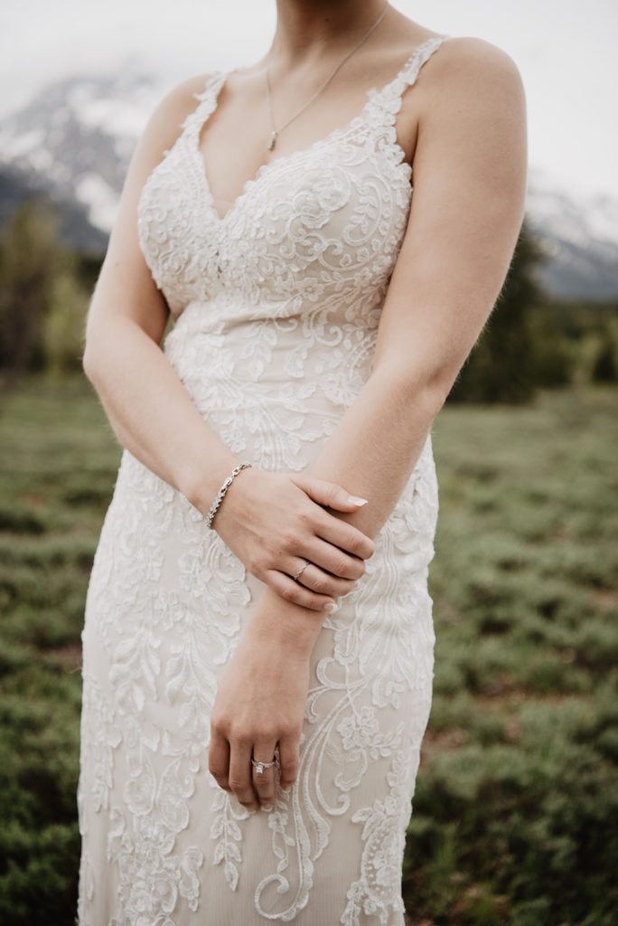 bride in a lace wedding dress posing in a field for her grant teton wedding with her jackson hole photographers