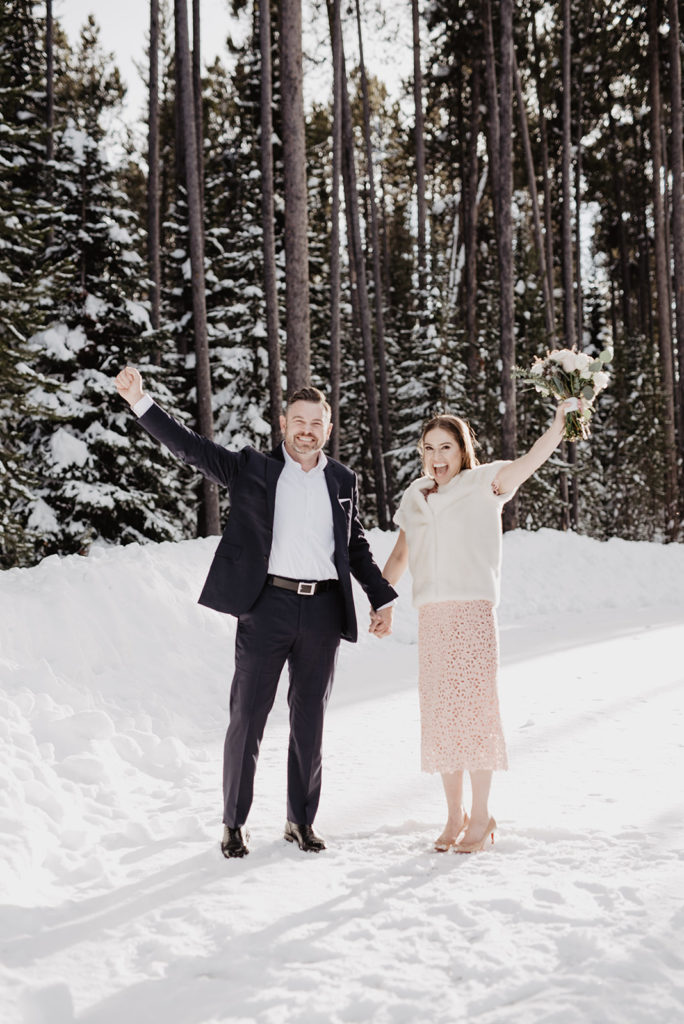 bride and groom holding hands and raising their arms in the air in celebration for the Jackson Hole wedding in the woods with Jackson Hole wedding photographer