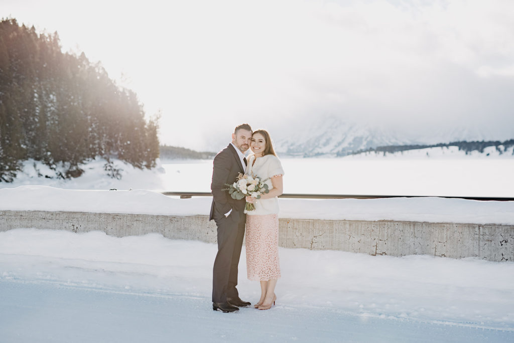 bride and groom embracing each other on a bridge int he Tetons with Jackson Hole wedding photographer for their outdoor winter bridals 
