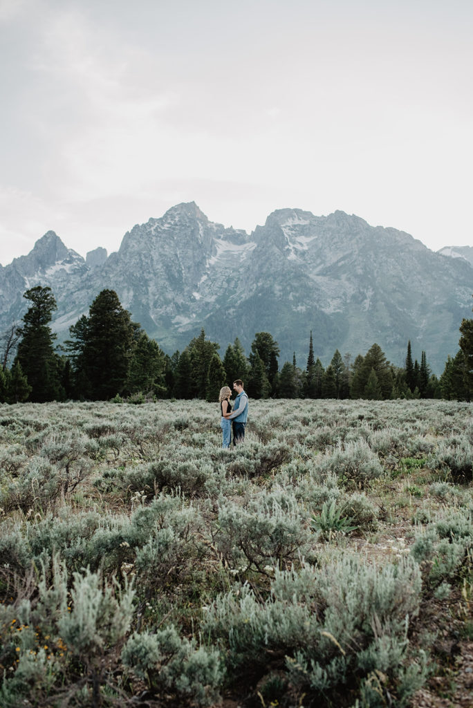 honeymoon photos with man and woman embracing in a meadow in the grand tetons 