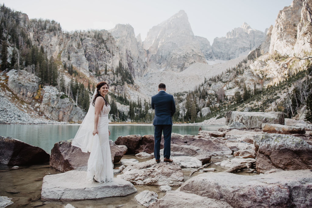 Grand Teton wedding with Jackson Hole photographer with bride standing behind the groom and walking towards him for their first look 