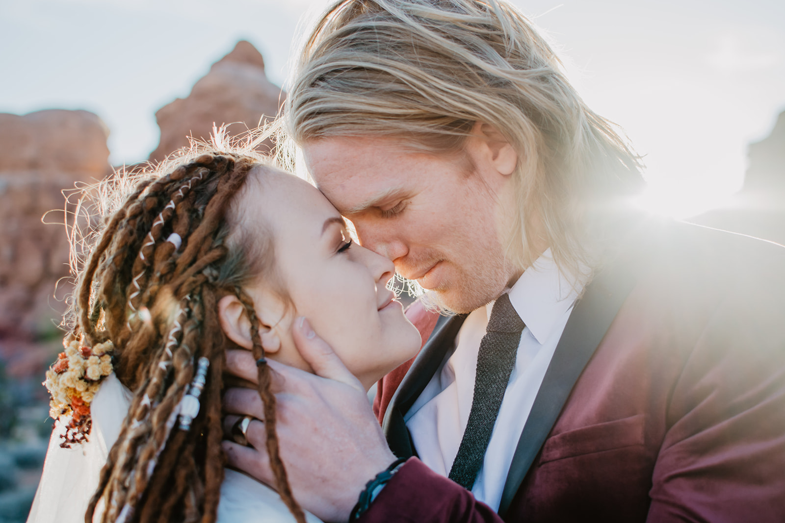 Utah elopement photographer captures bride and groom just as they are about the kiss with the sun shining in the distance for their Arches National Park wedding