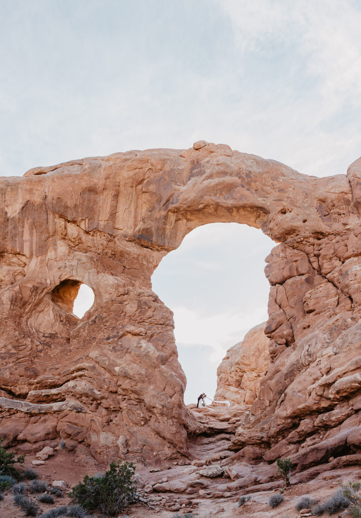 Arches National Park wedding with Utah elopement photographer with bride and groom under an arch while embracing each other 