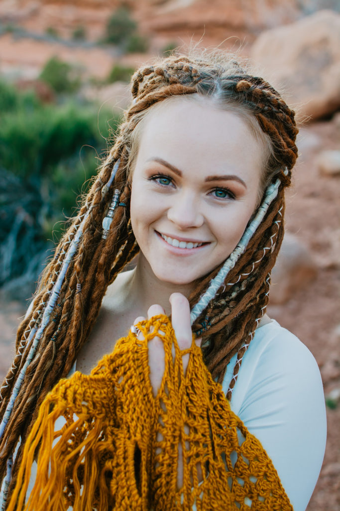 southern utah bride with dreads and wearing a satin wedding dress with an orange shawl posing for bridal portraits with Utah elopement photographer 