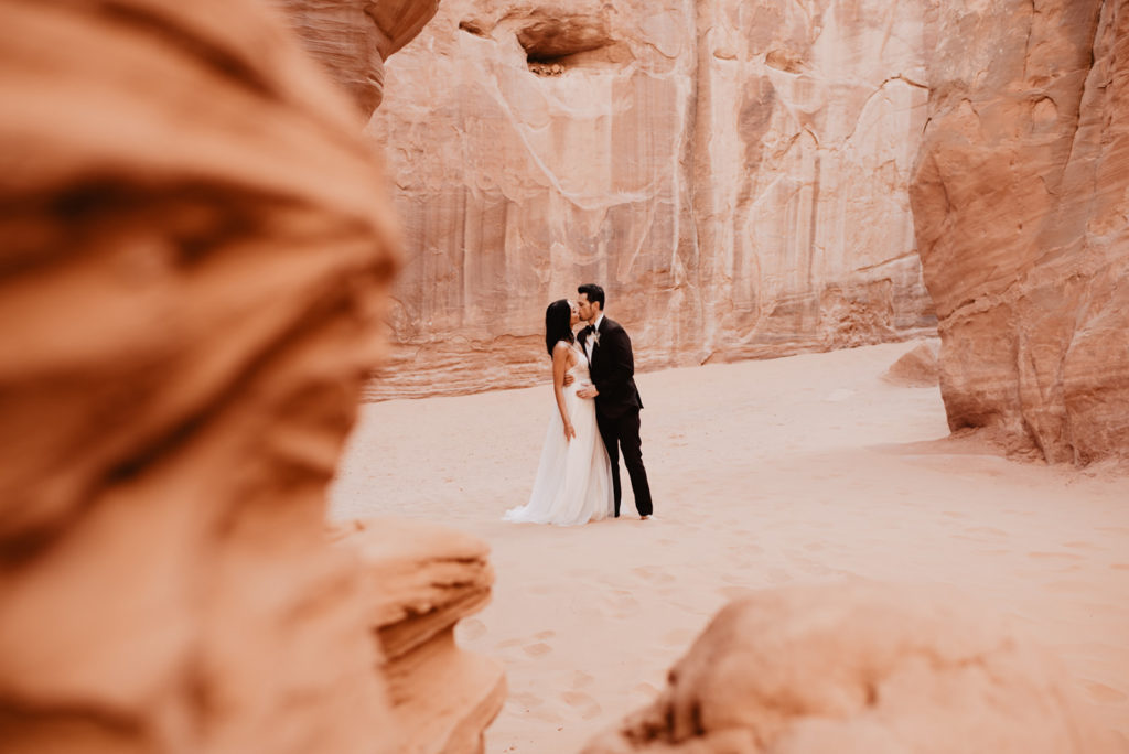 utah elopement photographer photographs bride and groom kissing in a red rock cave for their Arches National Park wedding 