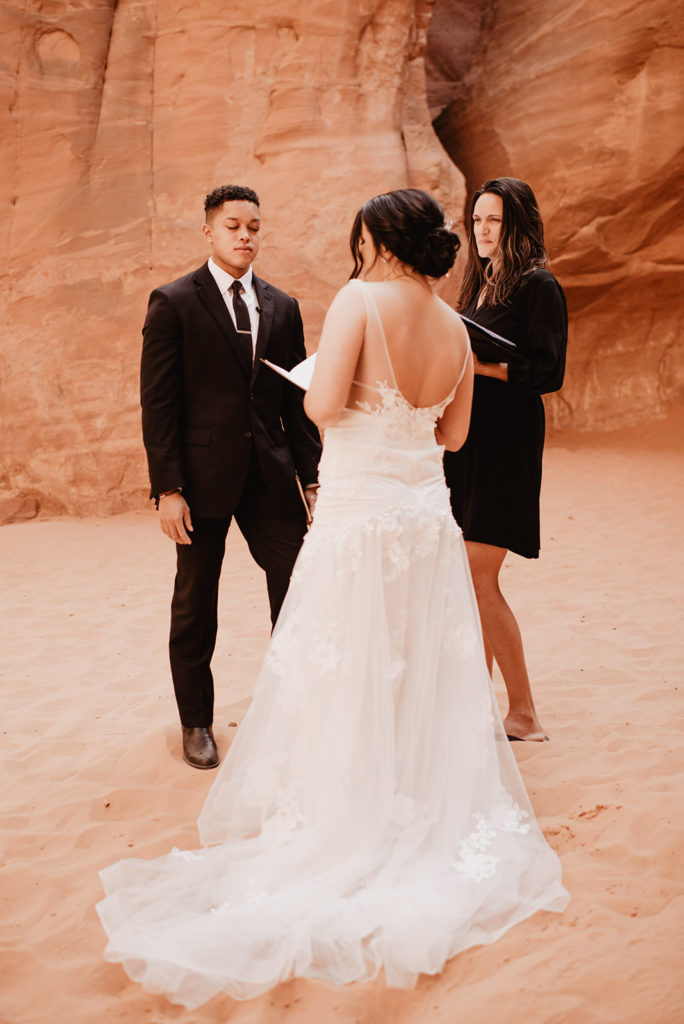 Arches National Park wedding ceremony with bride holding a piece of paper and reading her vows to her groom captured by Utah elopement photographer 