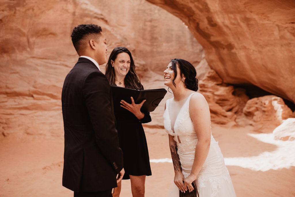 bride and groom reading their vows and laughing together for their Arches National Park wedding captured by Utah elopement photographer 