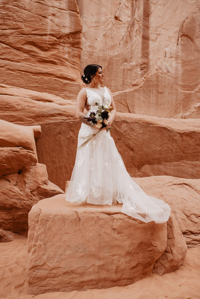 Utah Elopement Photographer captures bride holding bouquet while standing on red rock in Rocky Mountain Bride magazine feature photo