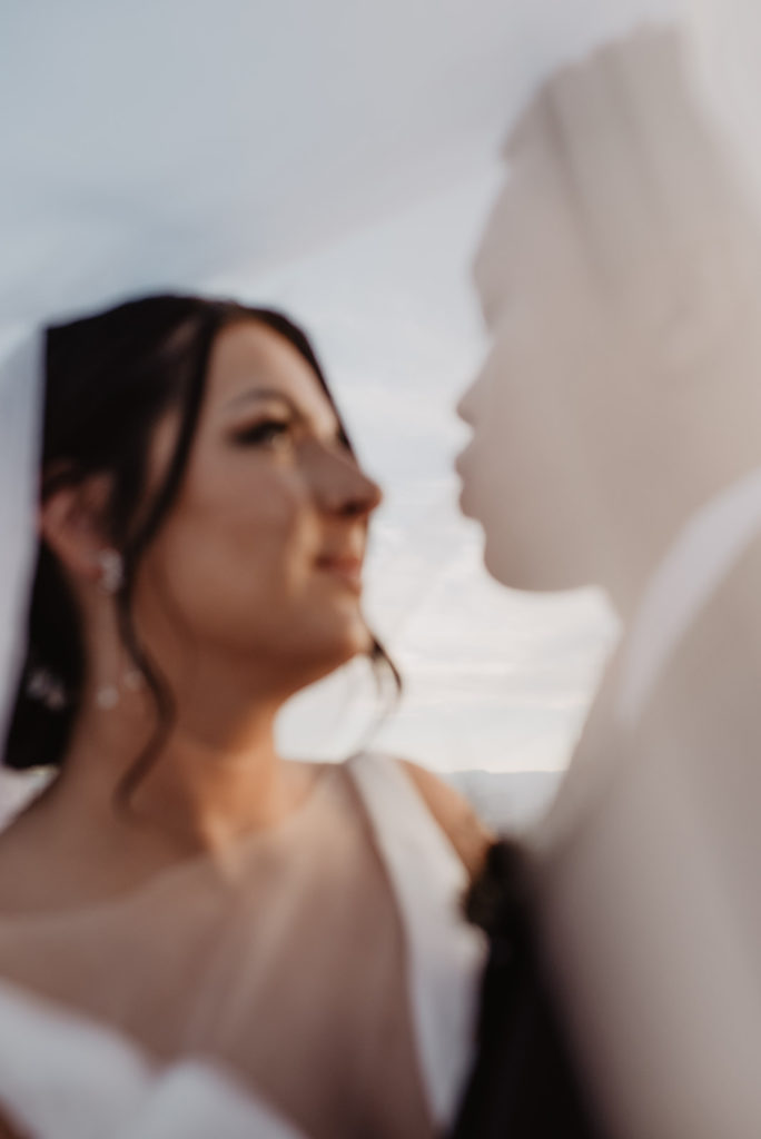 bride and groom embracing under the brides wedding veil photographed by Utah elopement photographer