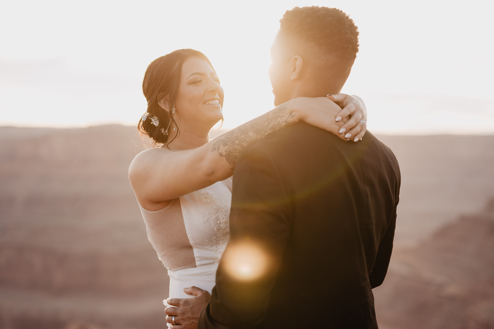 sunset wedding pictures with bride holdin gher arms around her groom and smiling as the sun sets over her head while she smiles captured by Utah elopement photographer