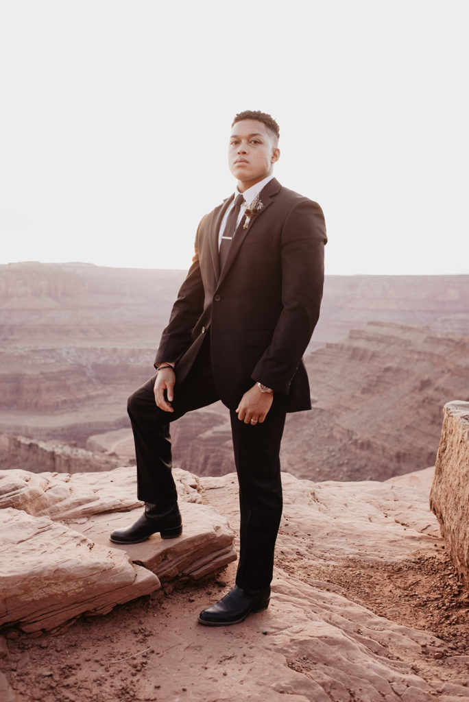 sunrise session with groom on top of a mountain in a black suit and tie captured by utah elopement photographer 