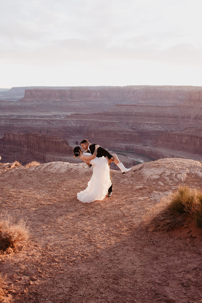 bridal portraits by utah elopement photos with couple dancing together on the top of a mountain in the desert