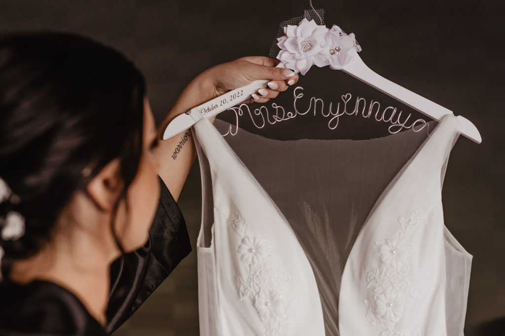 Utah elopement captures bride holding up her wedding dress on a hanger in her bridal suite before her Utah elopement
