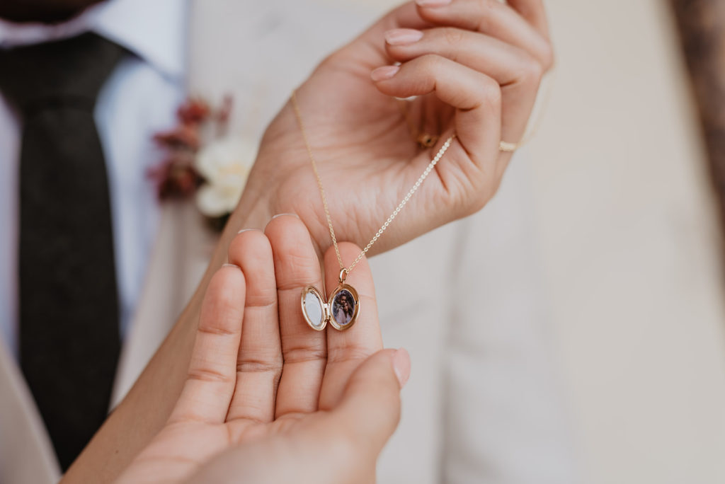 detail shot of bridal gift from the groom with bride holding a small locket necklace captured by utah elopement photographer