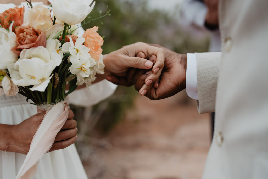 detail shot of groom holding his brides hand during their wedding ceremony ay Arches National Park photographed by Utah Elopement Photographer