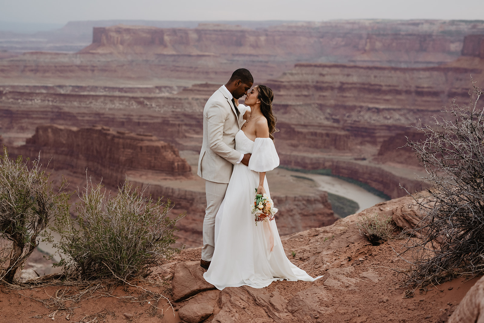 sunset Arches National Park wedding captured by Utah elopement photographer with bride and groom holding each other on red rock mountains