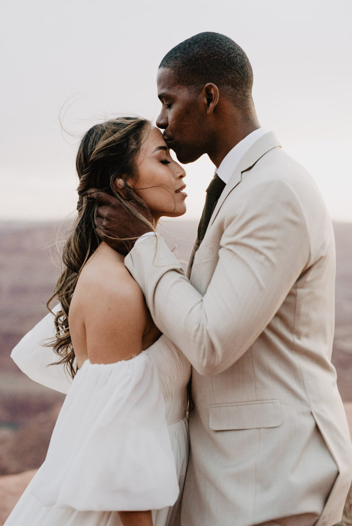 romantic moment with bride adn groom embracing as the groom kisses his brides forehead and holds her face gently captured by Utah elopement photographer