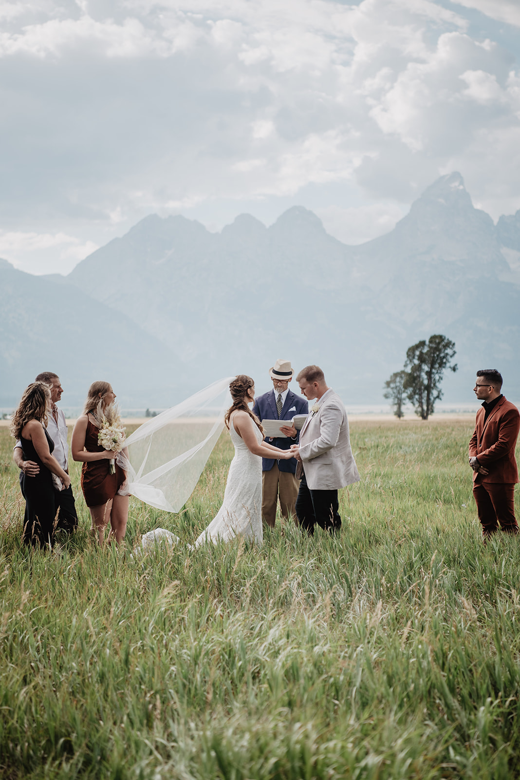 Jackson hole elopement photographer captures outdoor wedding ceremony in the Grand Tetons with bride and groom in a field together