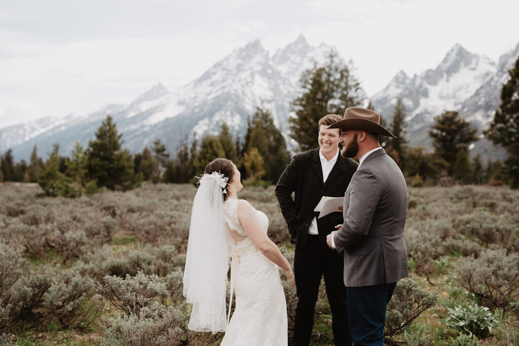 outdoor ceremony in the Tetons with bride and groom laughing with their officiant captured by Jackson Hole photographer