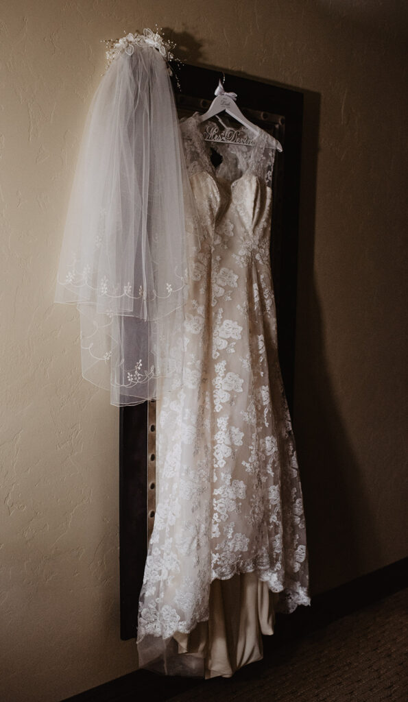 jackson hole photographers photographs heirloom wedding dress hanging on a door in a hotel room for wyoming elopement