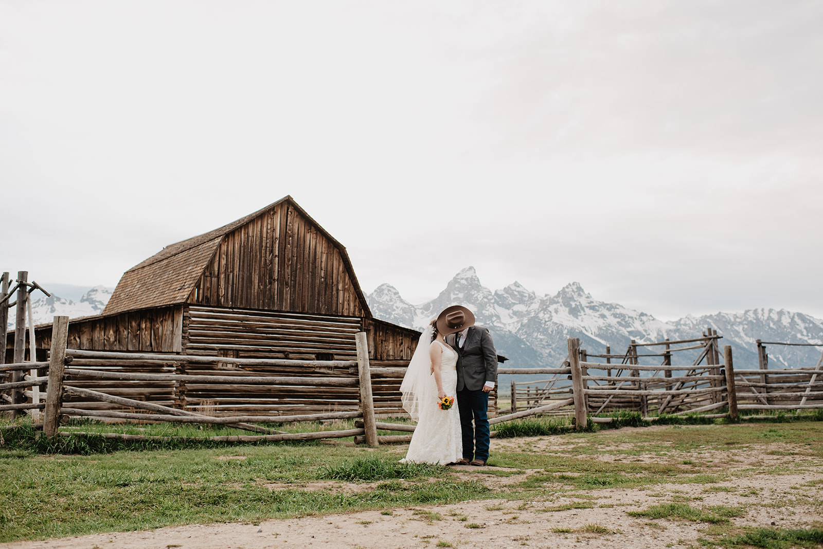 bride and groom kissing one another in front of an old historic barn for their grand teton elopement portraits with jackson hole photographer