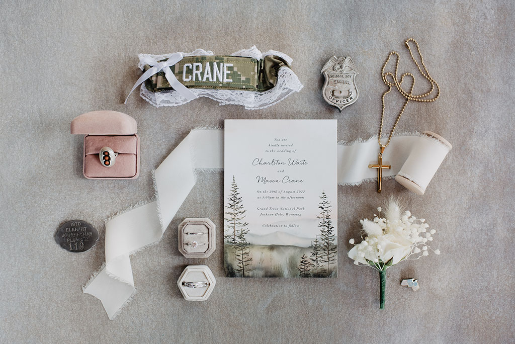 jackson hole photographers photographs wedding detail sin a flatlay including wedding invitations, florals, rings and garter