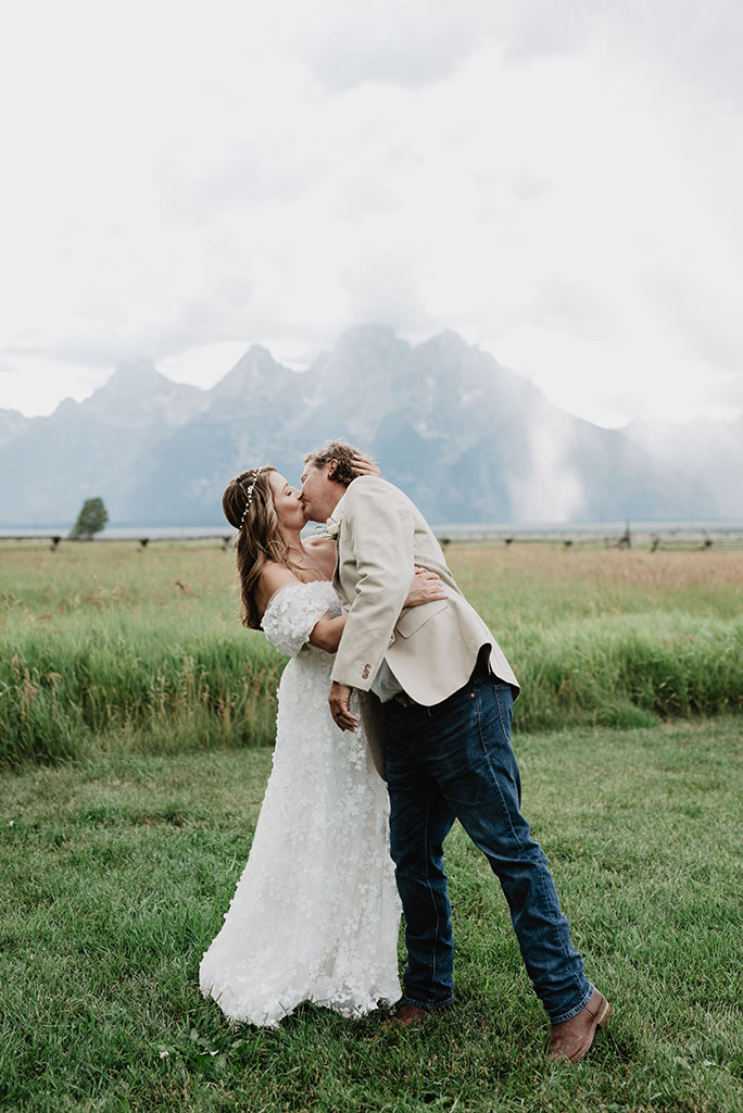 jackson hole photographers captures outdoor elopement in the Tetons with bride and groom kissing passionately in a field in front of the mountains