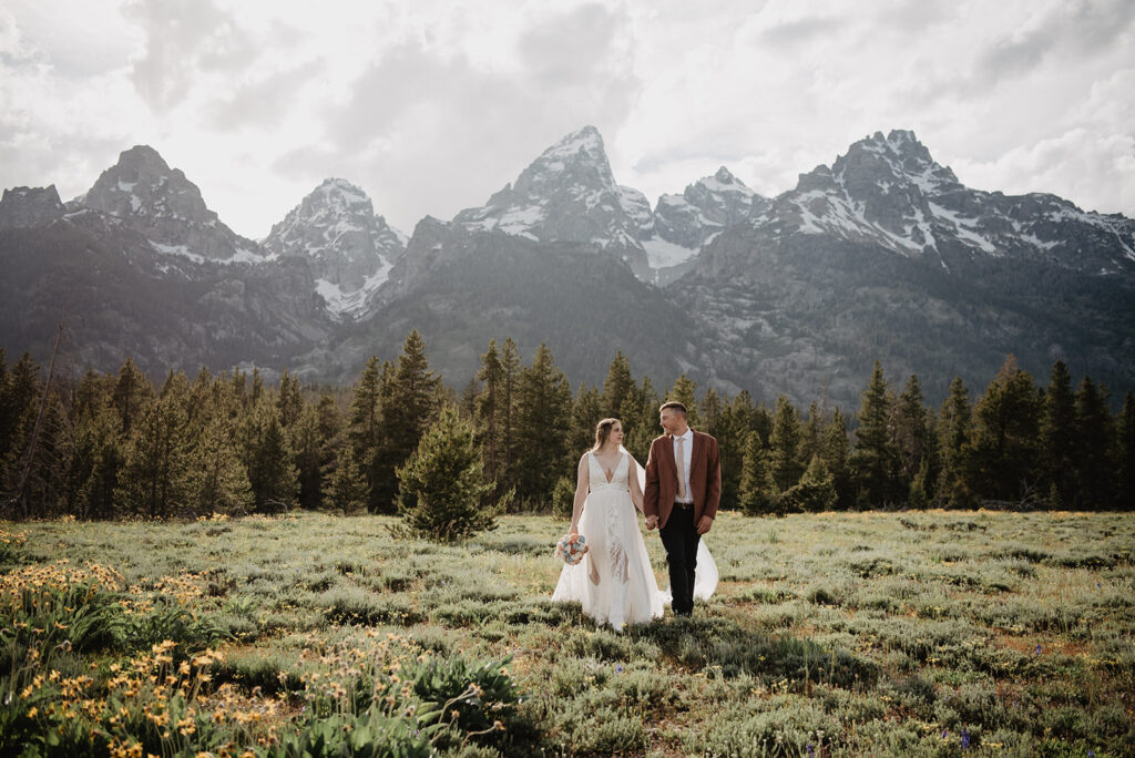 Jackson Hole elopement photographer captures bride and groom walking through field together