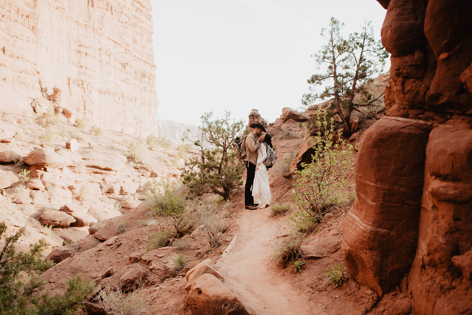 Utah elopement photographer captures bride and groom hiking through arches national park for their utah elopement surrounded by brush and red rocks