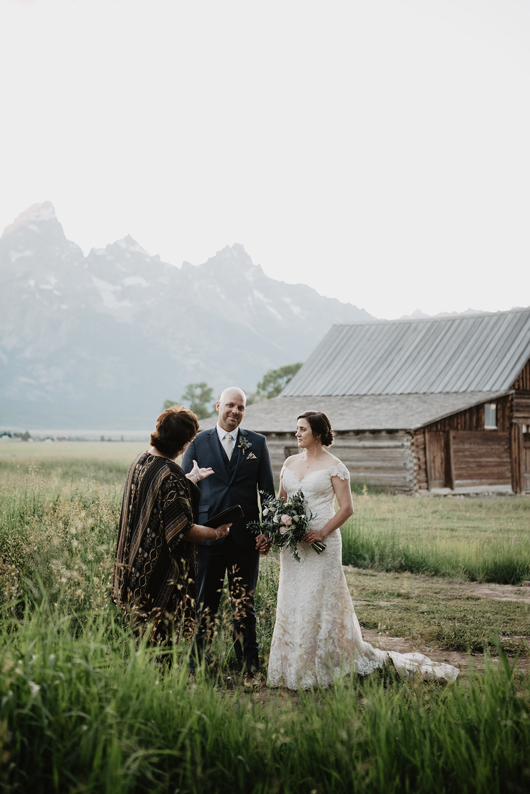 outdoor elopement ceremony at mormon row in the tetons with officiant speaking with the couples as they hold hands and prepare to share their vows together captured by Jackson Hole wedding photographers