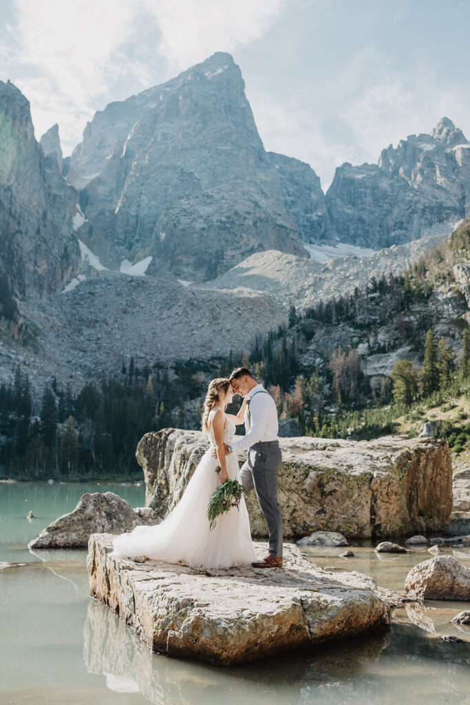 Jackson Hole photographer captures couple wearing wedding attire on rock in Jackson Hole elopement