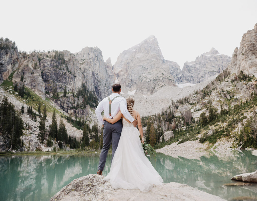 Jackson Hole photographer captures couple hugging and looking at Grand Tetons in Jackson Hole elopement