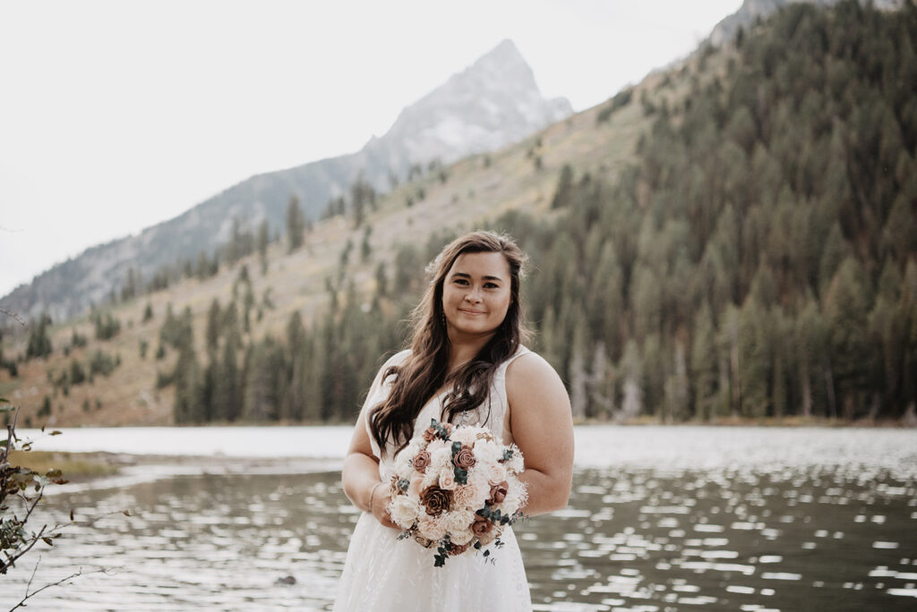 Photographers Jackson Hole capture bride holding bouquet smiling at camera 