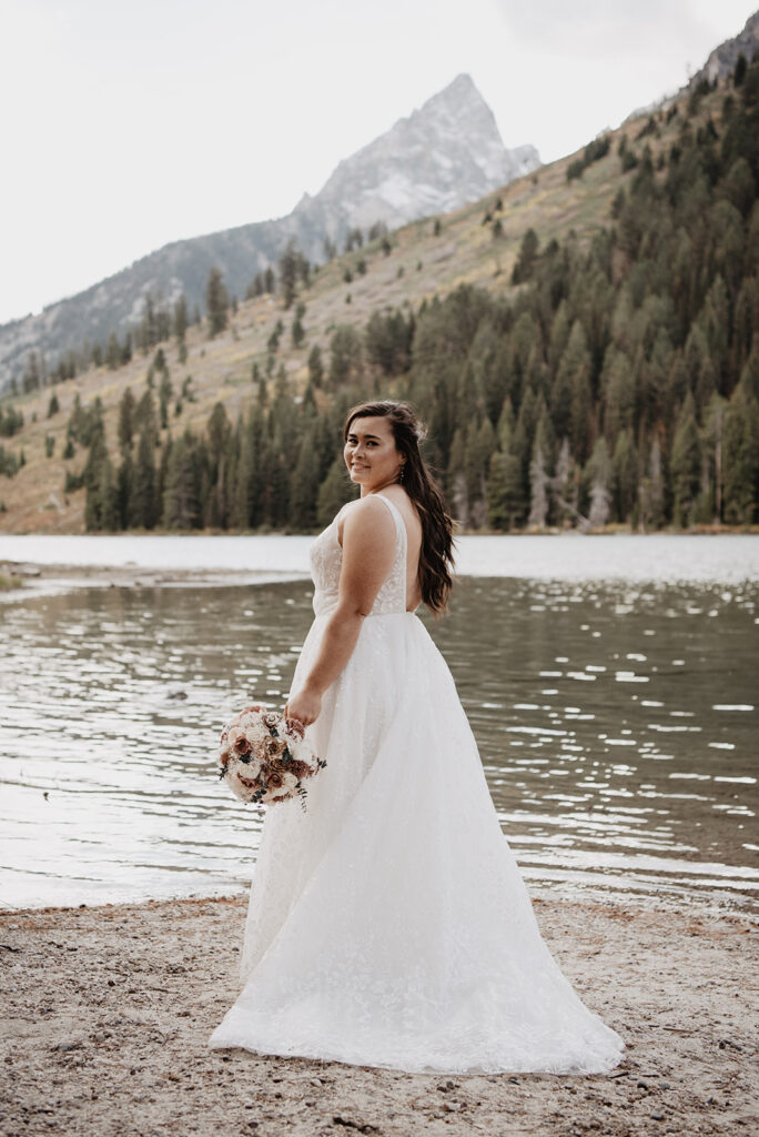 Photographers Jackson Hole capture bride wearing wedding dress and looking over shoulder