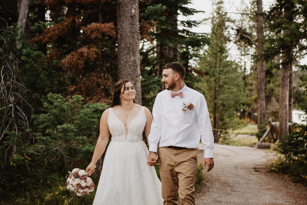 Photographers Jackson Hole capture couple walking through forest holding hands after Jackson Hole elopement