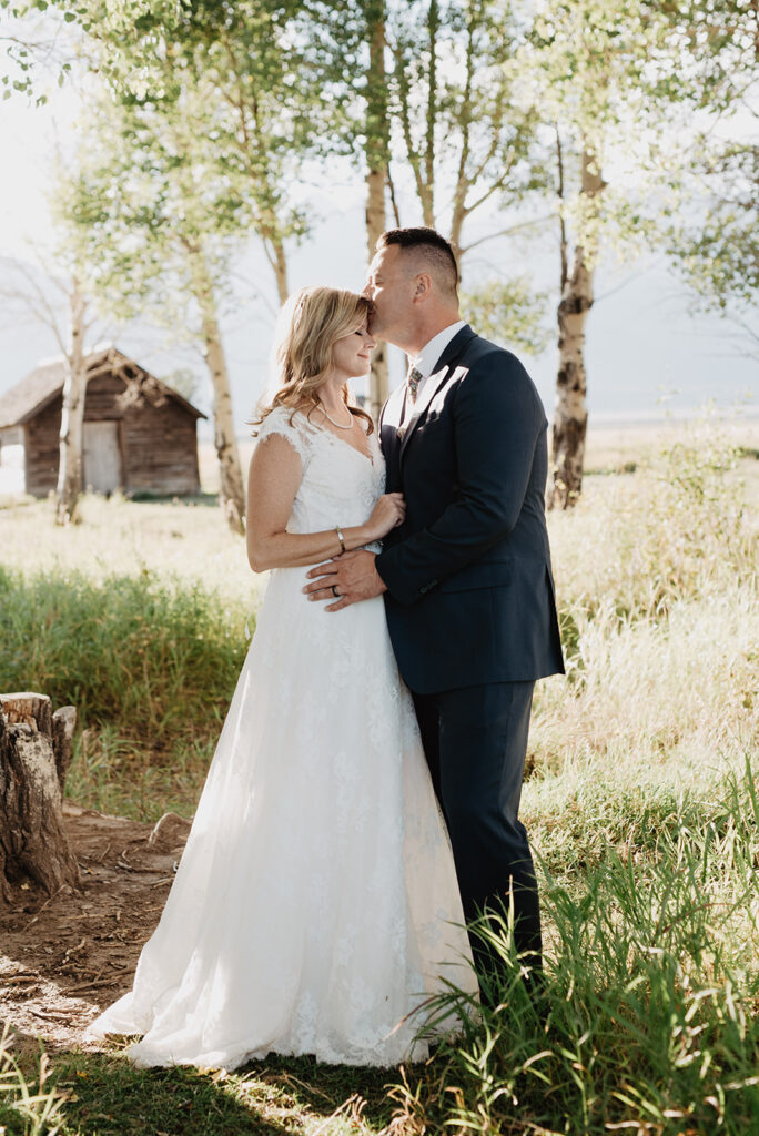 Photographers Jackson Hole capture groom kissing bride's forehead