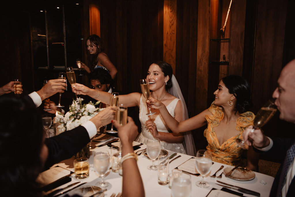 Jackson Hole wedding photographer captures bride and groom celebrating with champagne at reception dinner
