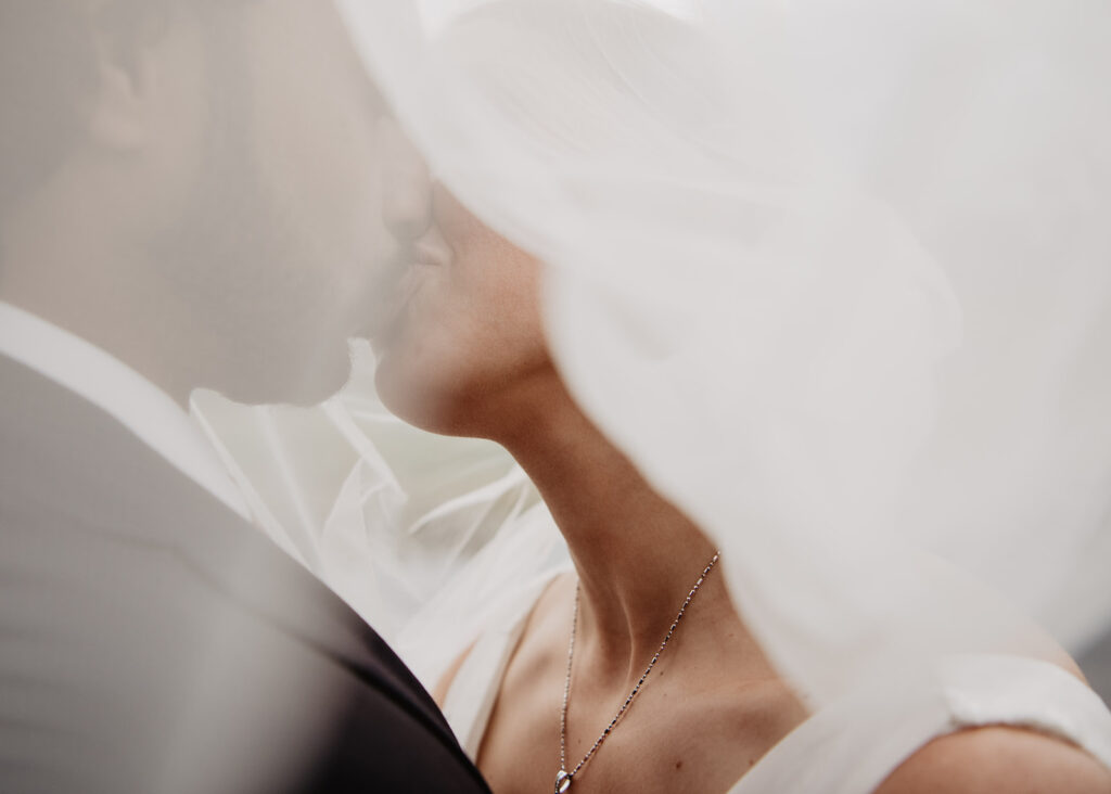 Jackson Hole wedding photographer captures bride and groom kissing under veil