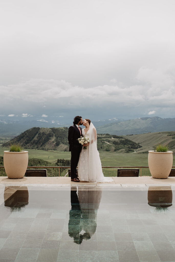 Jackson Hole Wedding Photographer captures bride and groom looking at landscape view in front of pool