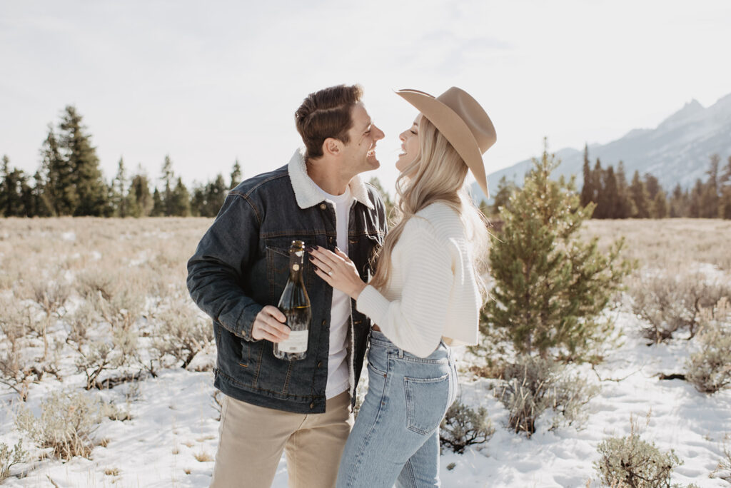 Jackson Hole wedding photographer captures couple celebrating recent engagement with champagne
